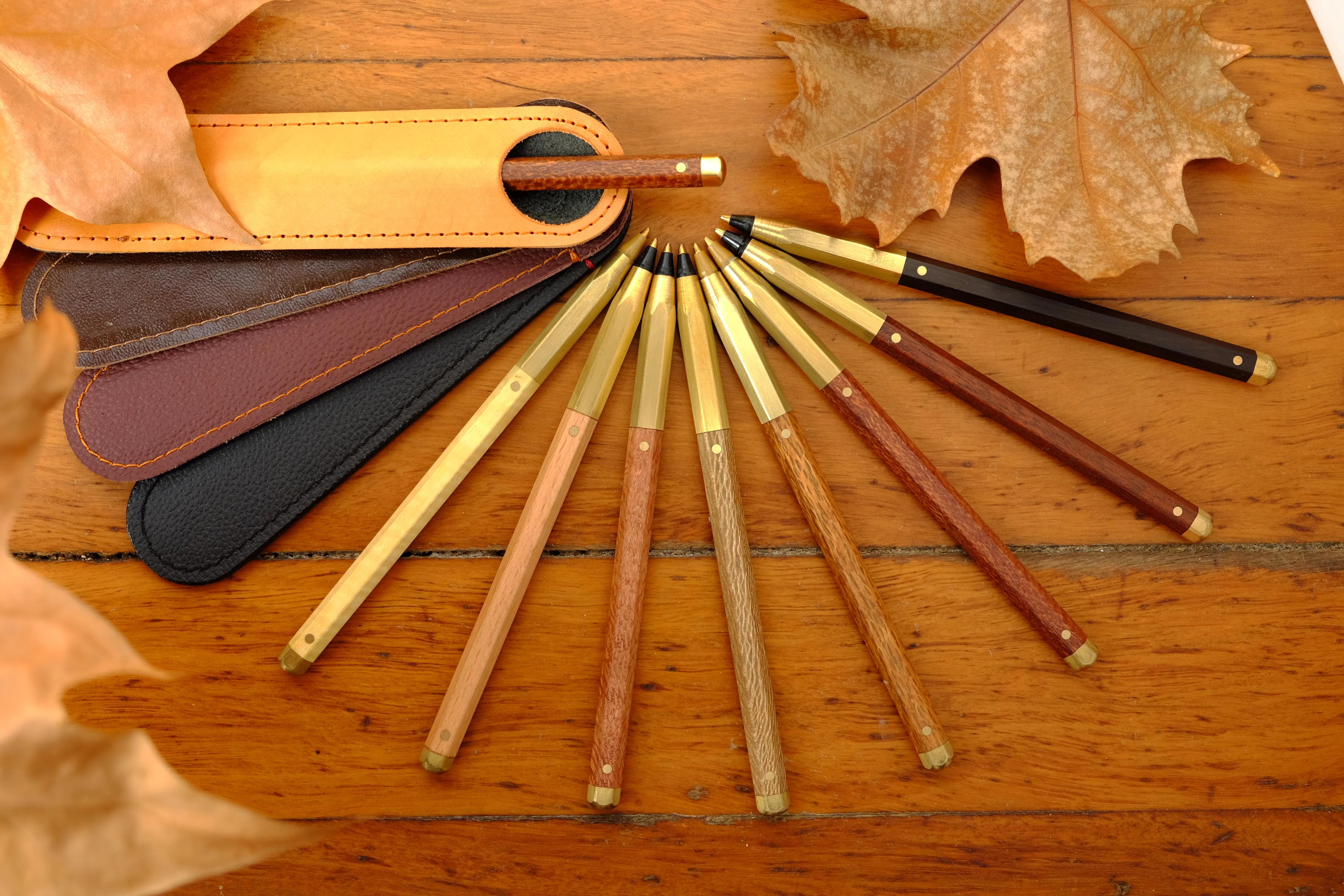 Object Works pens, timber barrels with brass fittings, fanned out beside leather sleeves